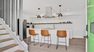 A modern kitchen with a central island, bar stools, and pendant lighting.