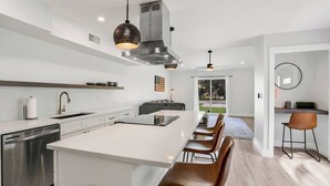 Uma cozinha moderna com uma ilha central, eletrodomésticos de aço inoxidável e uma área de jantar com banquetas.