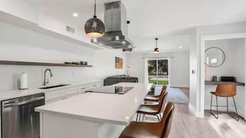 A modern kitchen with a central island, stainless steel appliances, and a dining area with bar stools.