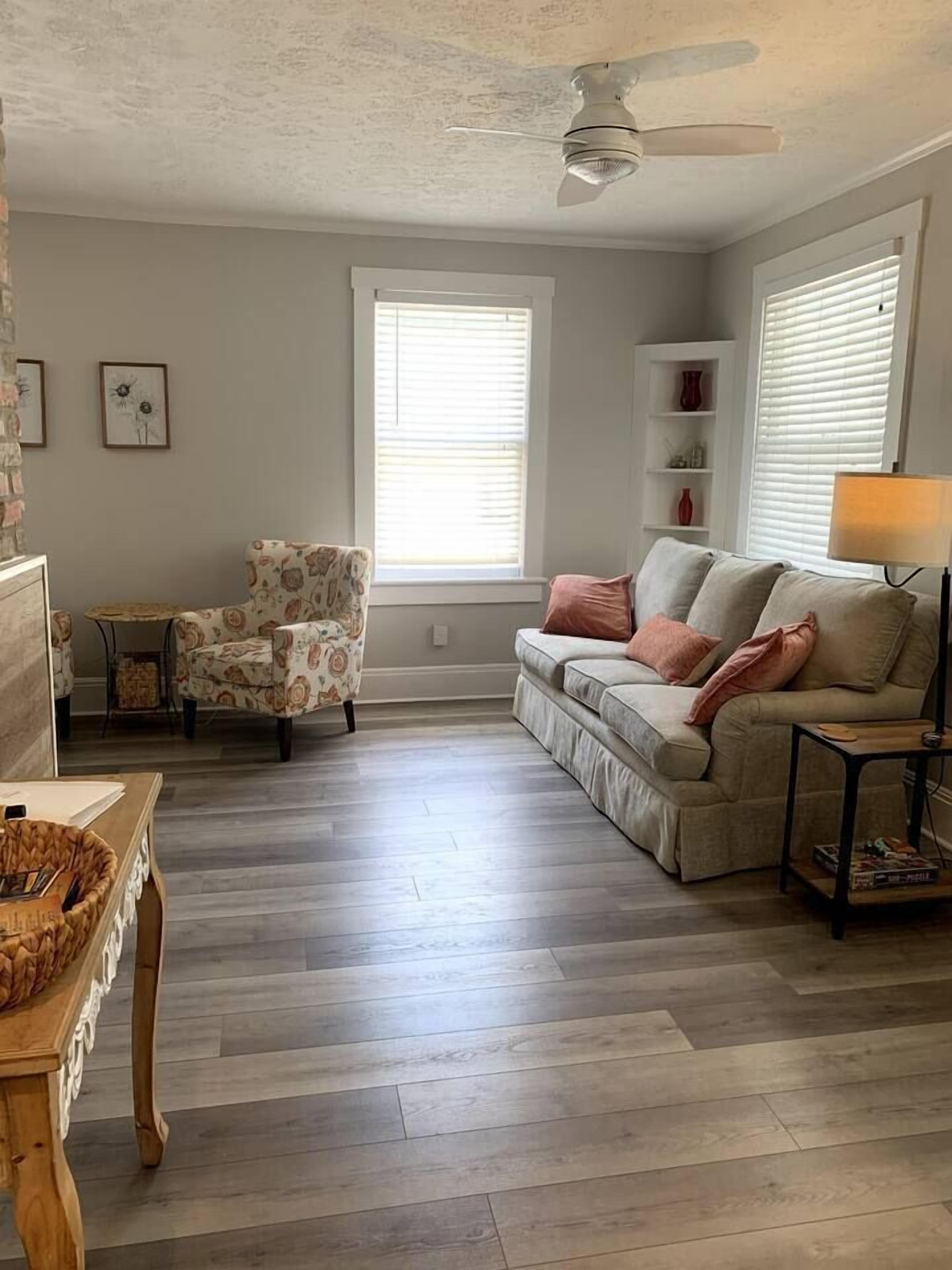 Una sala de estar con sofá, sillón y una mesa con lámpara.