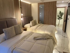 Ein Hotelzimmer mit zwei Betten, einem Holzkopfstück, einem Nachttisch, einem Spiegel und einer Topfpflanze.