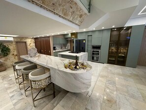 A modern kitchen with a marble island, bar stools, and built-in appliances. - Exclusive penthouse rooftop pool, luxury living and beach (Cartagena de Indias)