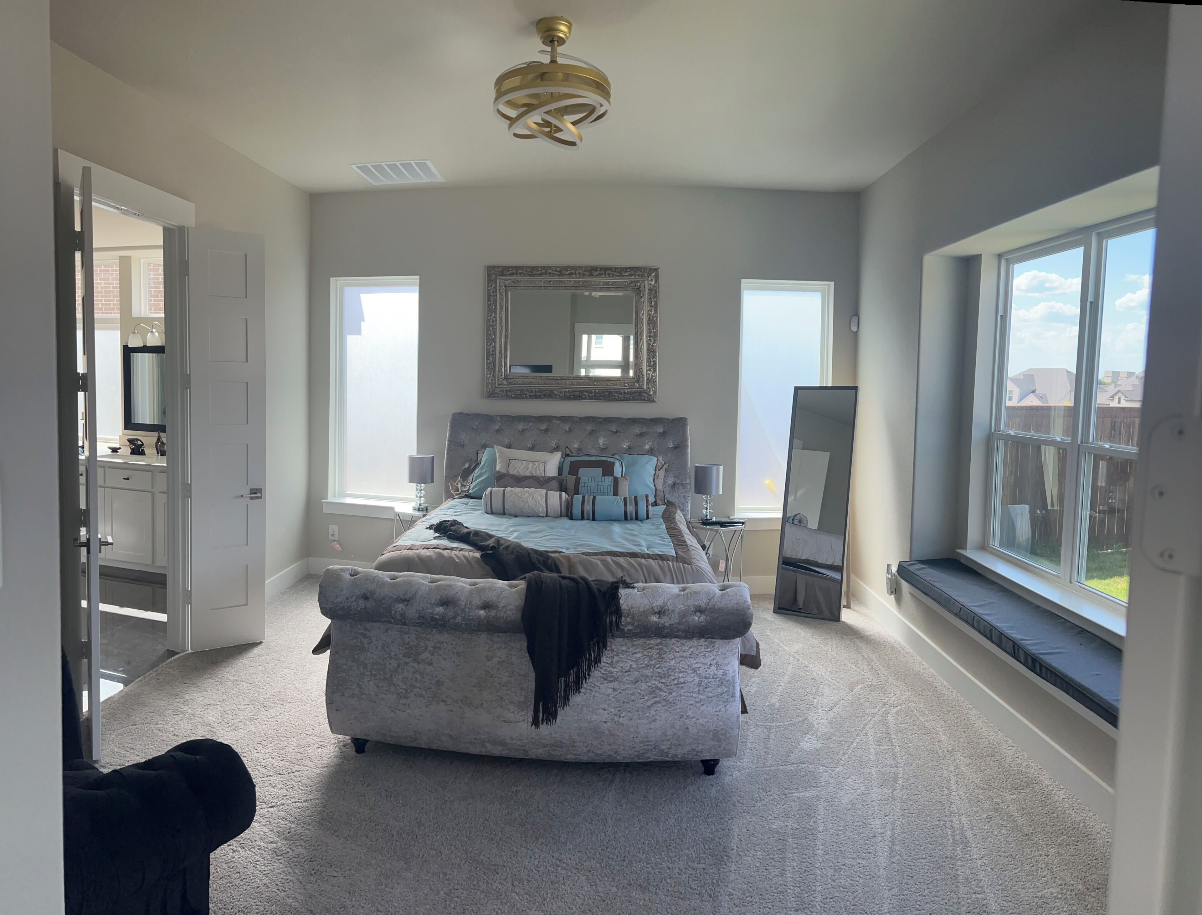 A bedroom with a large bed, a sitting area, a mirror, and a window.