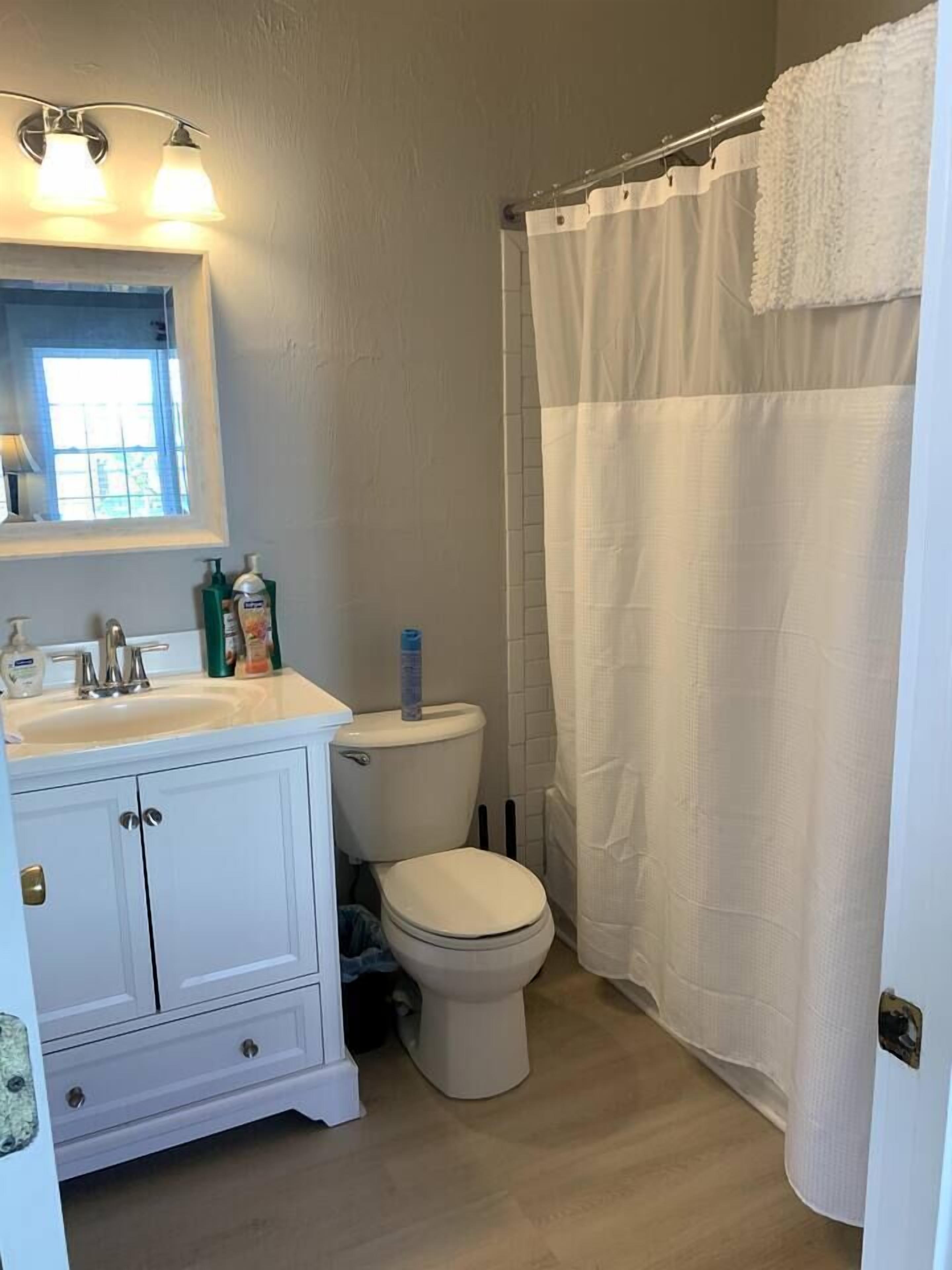 Une salle de bain avec un lavabo blanc, des toilettes et un rideau de douche.