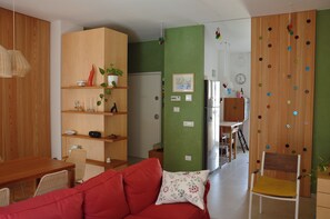 A modern living room with a red sofa, wooden shelving, a dining area, and a kitchen in the background. - Casa Fortu in centro. Luxury house with an alcove in the heart of Bari. (Bari)