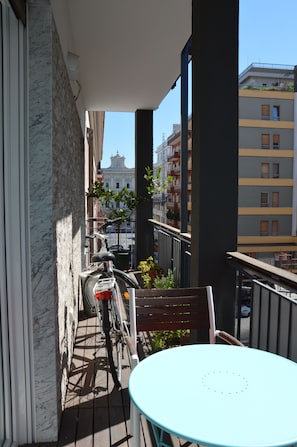 A balcony with a bicycle, a table, and a view of buildings in the background. - Casa Fortu in centro. Luxury house with an alcove in the heart of Bari. (Bari)