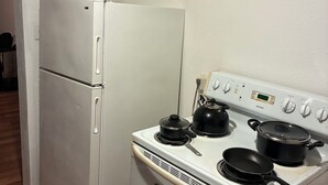 Une cuisine avec un réfrigérateur blanc, une cuisinière avec des casseroles et un four à micro-ondes.