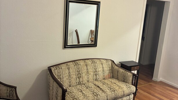 Un salon avec un canapé, une table basse et un miroir au mur.