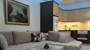 En stue med sofa, sofabord og et billede på væggen.