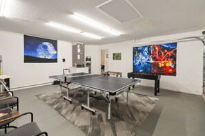 Een kamer met een tafeltennistafel, een tafelvoetbaltafel en Star Wars posters aan de wanden.