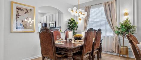 A dining room with a wooden table set for six, surrounded by upholstered chairs with a patterned design.