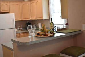 A kitchen counter with a plate of food, two wine glasses, and a bottle of wine. - Cozy & Comfy 2/2 Apt ~ Walk to Historic Downtown (St. Augustine)