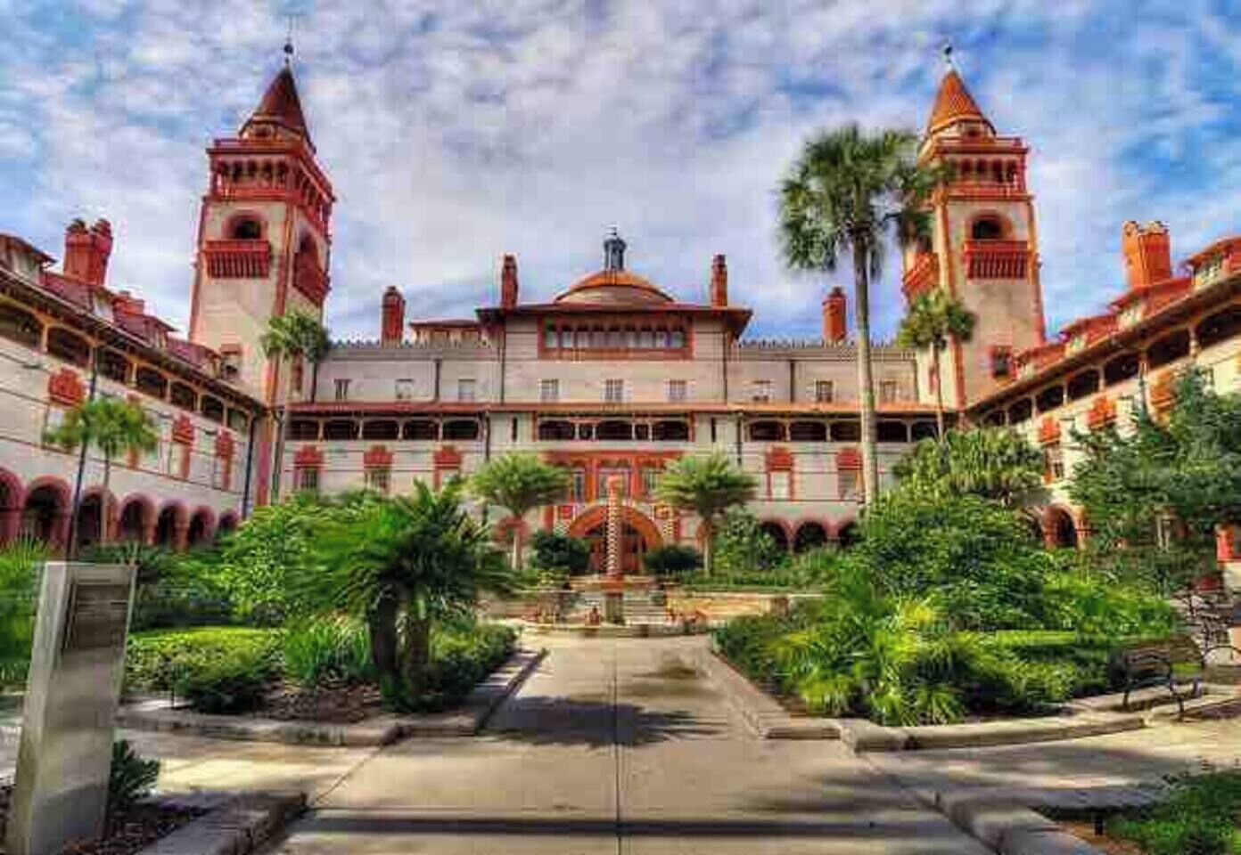 A large building with a central courtyard, multiple towers, and surrounding greenery.