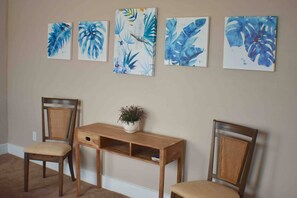 Een kamer met een houten bureau, twee stoelen en vier wanddecoraties.