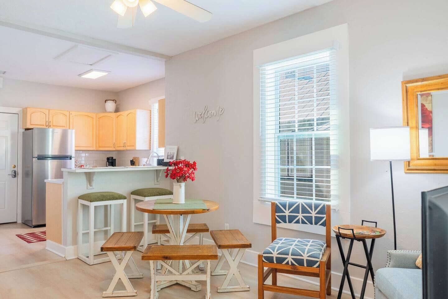 A modern kitchen with a refrigerator, wooden cabinets, and a dining area with a table and chairs.
