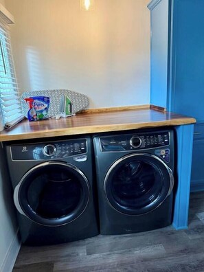 A laundry area with two front-loading washing machines and a wooden countertop. - 2BR/2B Home-Walk to St. Aug (St. Augustine)