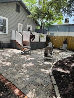 A backyard with a paved patio, outdoor furniture, and a wooden fence. - Casa Carrera 2BR/2BA Main Cottage - Walk to Town (St. Augustine)