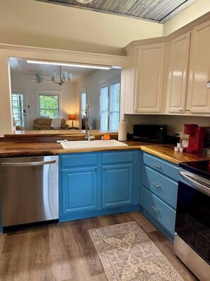 A kitchen with a wooden countertop, blue cabinets, a stainless steel dishwasher, and a red coffee maker. - 2BR/2B Home-Walk to St. Aug (St. Augustine)