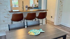 Uma área de refeições com uma mesa, quatro cadeiras e um jogo americano decorativo.