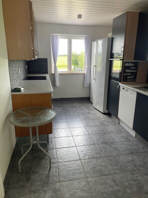 A kitchen with a refrigerator, oven, and a window with curtains. - Lovely big house - quiet and beautiful - with garden and fence for dogs (Horslunde)