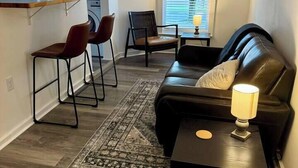 Ett kompakt vardagsrum med en soffa, två fåtöljer, ett litet bord och en lampa. En tvättmaskin syns i bakgrunden.