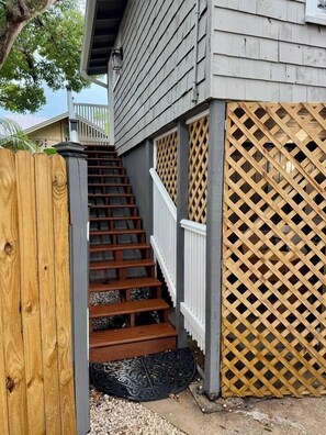 A wooden staircase leading to a deck, surrounded by a wooden fence and lattice panels. - Casa Carrera 1BR/1BA Easy Walk to Town (St. Augustine)