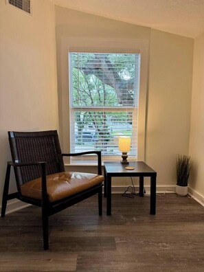 A corner room with a window, a chair, a small table with a lamp, and a potted plant. - 1BR/1BClean,CozyApt/Walk to town (St. Augustine)