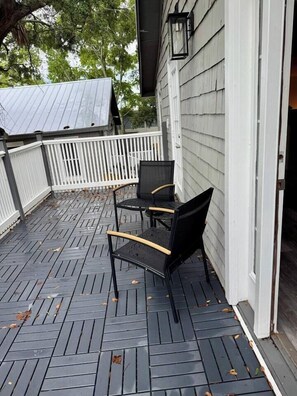 A covered outdoor area with a wooden deck, a white fence, and two black chairs. - 1BR/1BClean,CozyApt/Walk to town (St. Augustine)