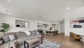 Ein modernes Wohnzimmer mit einer Couch, einem Couchtisch und einem Essbereich mit Stühlen.