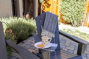 A chair with a plate of waffles and a mug, placed on a stone table outdoors.