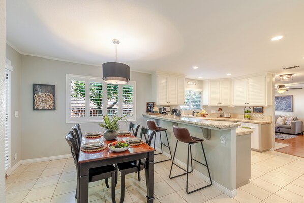 Una cocina moderna con una isla central, taburetes de bar y una mesa de comedor para cuatro.