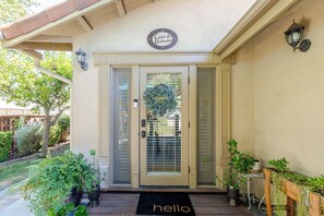 A house entrance with a 'Casa de Minos' sign, a door with a glass panel, and a 'hello' mat.