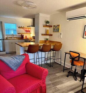 A compact living space with a kitchenette, a dining area with bar stools, a red sofa, and a small table with a chair. - Casa Carrera 2BR/1BA-Walk Downtown + Free Parking (St. Augustine)