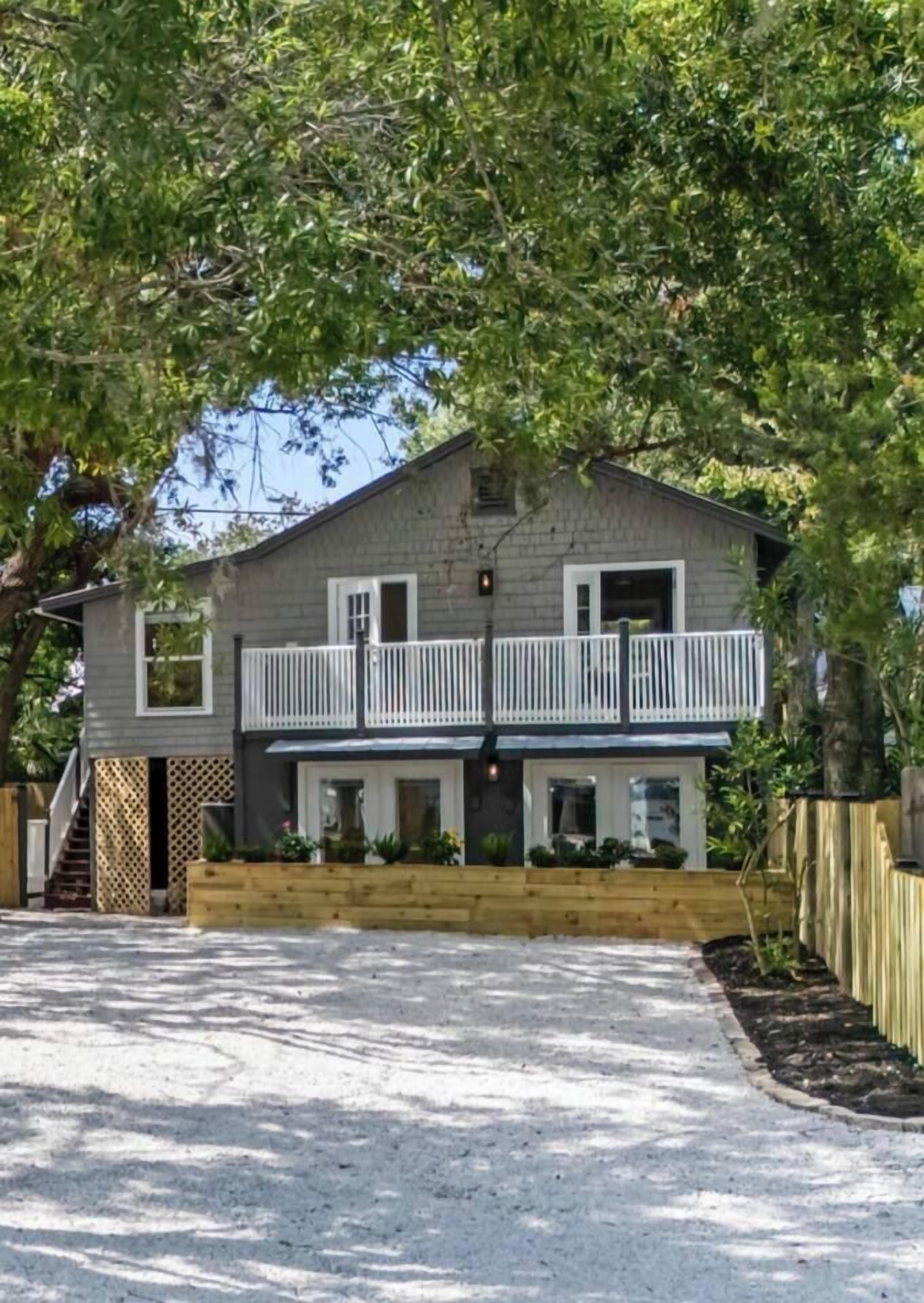 A two-story house with a balcony, a wooden fence, and a paved driveway.