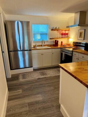 A kitchen with a stainless steel refrigerator, wooden countertops, and white cabinets. - Casa Carrera 2BR/1BA-Walk Downtown + Free Parking (St. Augustine)