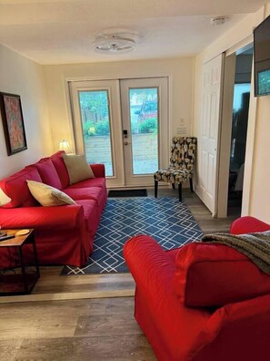 A living room with a red sofa, a patterned armchair, and a blue rug. - Casa Carrera 2BR/1BA-Walk Downtown + Free Parking (St. Augustine)