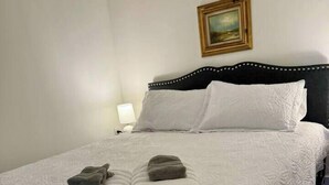 Ein ordentlich bezogenes Bett mit weißer Decke und zwei gefalteten Handtüchern am Fußteil.