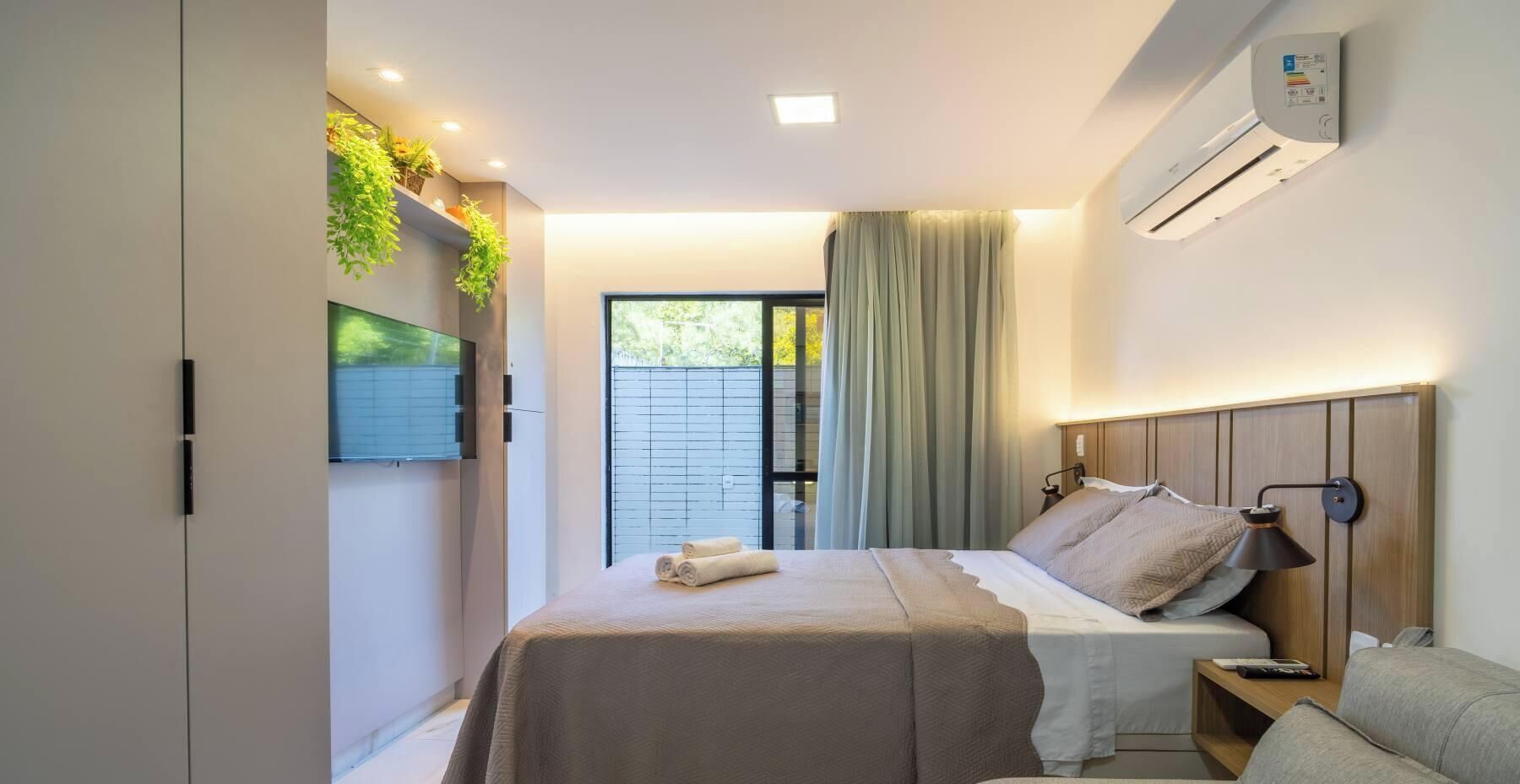 Une chambre à coucher moderne avec un lit, une table de chevet et un téléviseur fixé au mur.