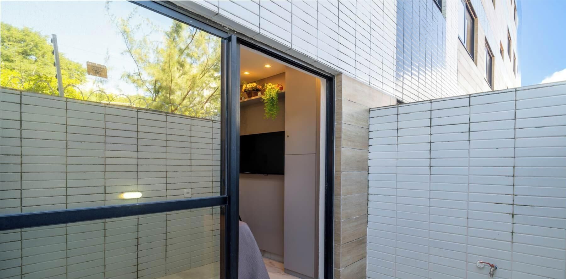 Un bâtiment moderne avec une entrée dotée d’une porte en verre, un espace extérieur bien visible et délimité par une clôture, et un ciel dégagé.