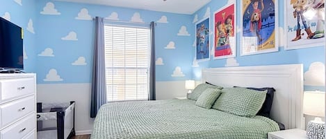 Un dormitorio con cama, mesita de noche, cómoda, ventilador de techo y adornos en la pared.
