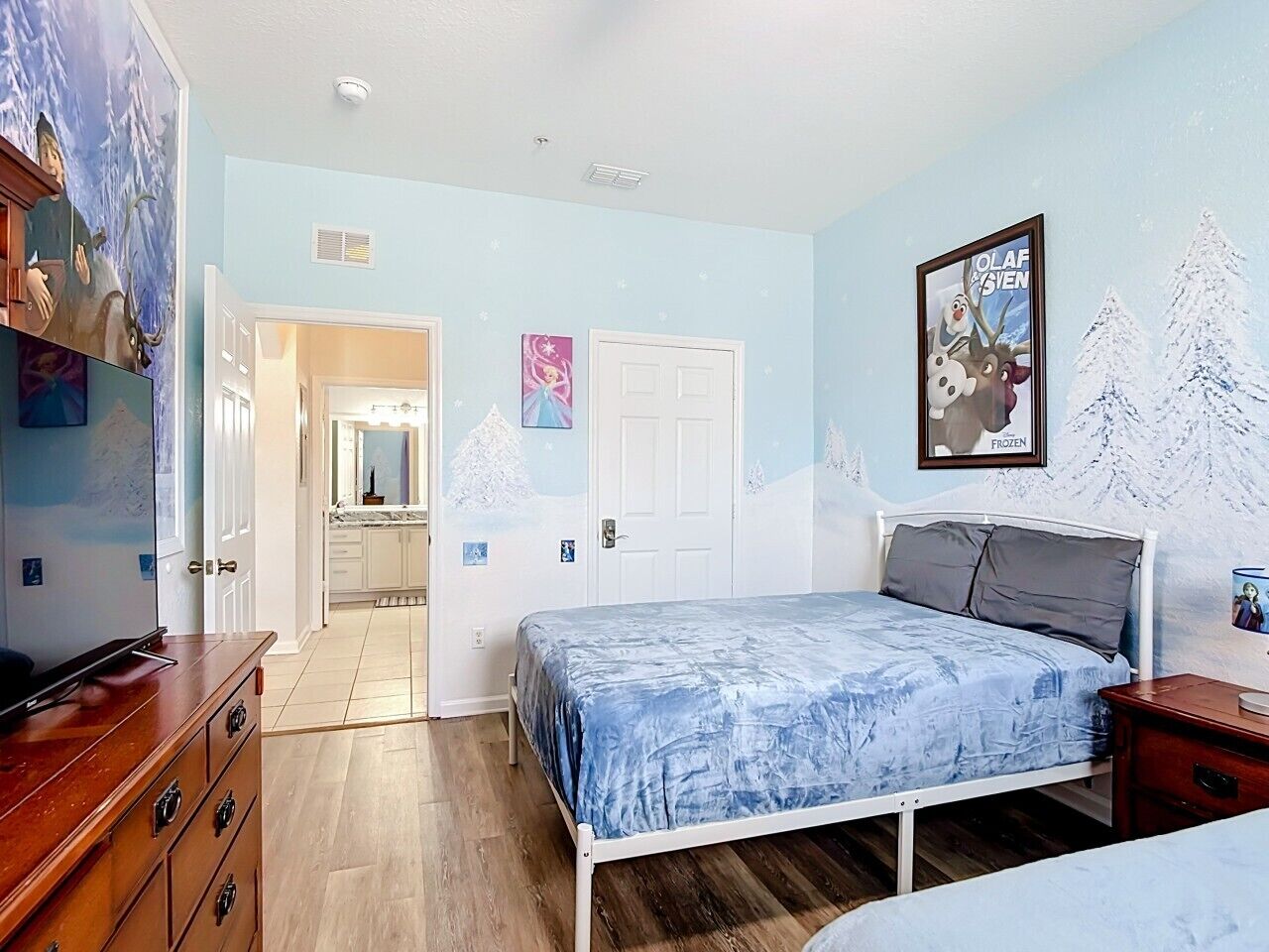 Une chambre à coucher comprenant un lit, une commode et une porte donnant sur une salle de bain.