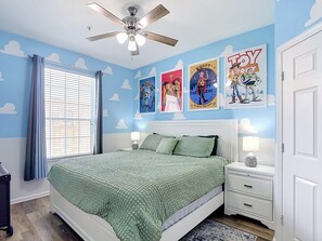 Ein Schlafzimmer mit einem Bett, Nachttischen, einem Deckenventilator und Postern an der Wand.