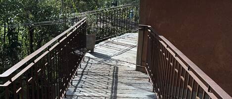 Una escalera de madera con barandillas metálicas que conduce a un edificio de fachada marrón.