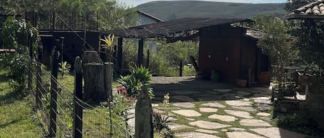 Un espacio exterior rústico con un sendero de piedra, construcciones de madera y un jardín cercado.