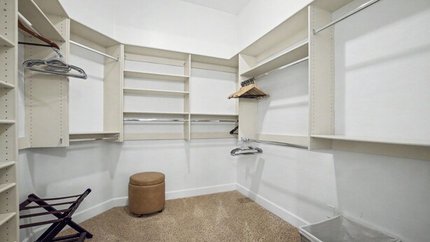 Um closet espaçoso com prateleiras abertas, cabideiro e um cesto de armazenamento.