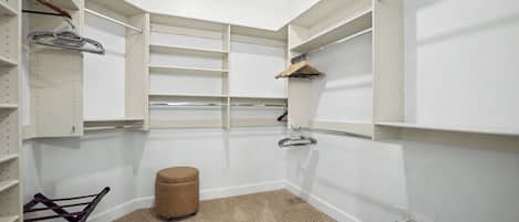 A walk-in closet with open shelving, a hanging rack, and a storage bin.