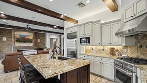 Cozinha moderna com bancadas de granito, eletrodomésticos de aço inoxidável e uma ilha grande.