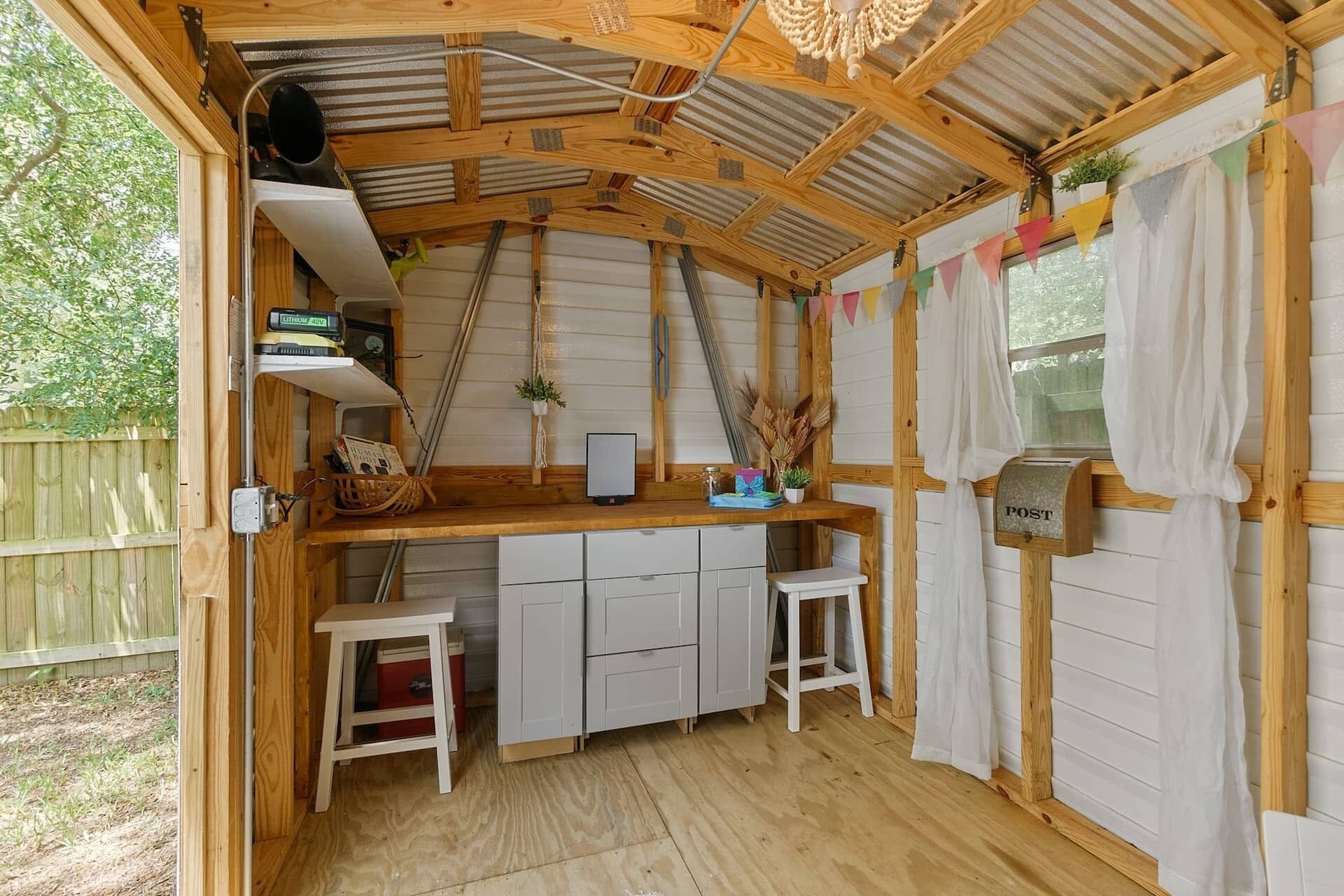 A compact kitchen with a wooden countertop, white cabinets, and a rustic ceiling.