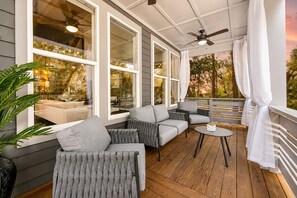 A covered outdoor seating area with grey sofas and a round table, large windows, and a ceiling fan. - St. Augustine with Private Pool Near Downtown (St. Augustine)