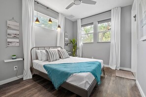 A bedroom with a bed, a ceiling fan, a window with curtains, and a plant. - St. Augustine with Private Pool Near Downtown (St. Augustine)